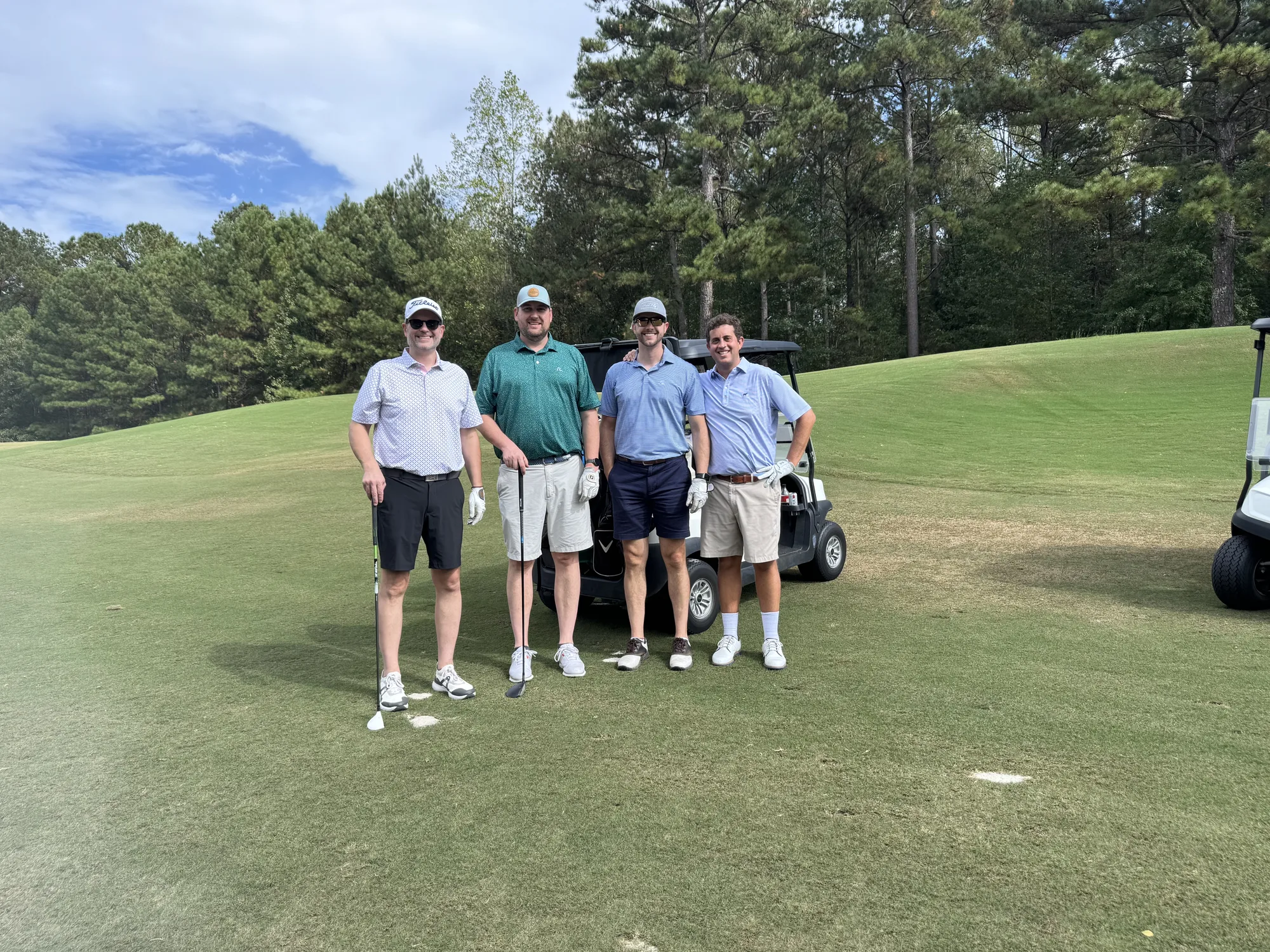 Golf Classic supporters gathered beside a sponsor sign.
