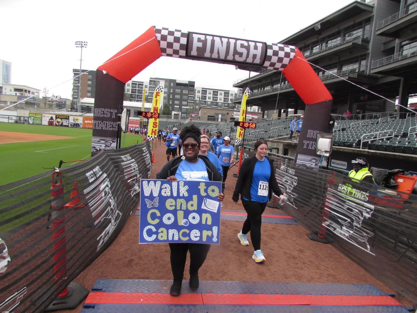 A participant carrying a Walk to End Colon Cancer sign at the finish line.